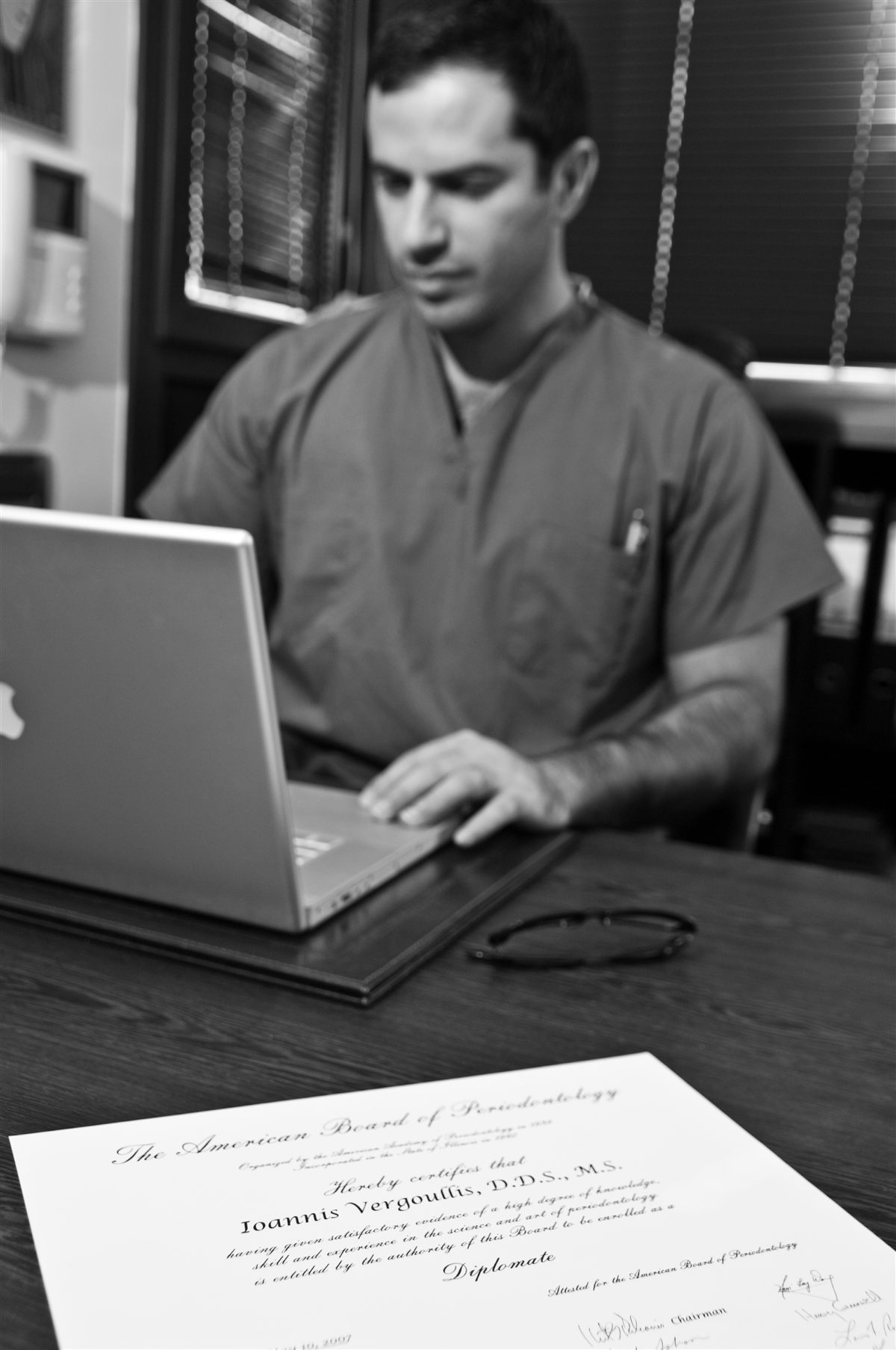 Dr. Ioannis Vergoullis at his desk, with his American Board of Periodontology diploma